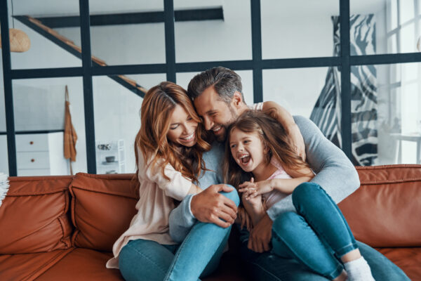 Happy young family with little girl preschool age smiling while bonding together at home